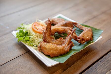 crispy chicken wing grilled in Thai style serve with tomato and vegetable on green banana leafの写真素材