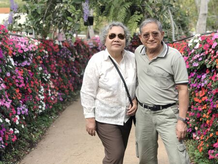 happy asian grandfather and grandmother happiness at outdoor activity to take photo at flower park. aging people with good healthの写真素材