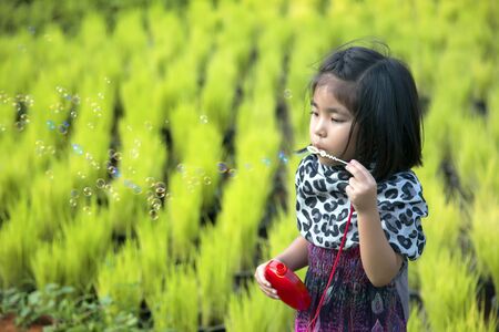cute asian kid playing bubble toy on green field. Beautiful outdoor activities momentの写真素材