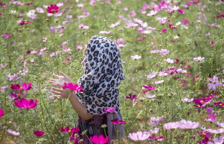 romantic moment of asian kid breezing on daisy flower agriculture field. Fashion action with natureの写真素材