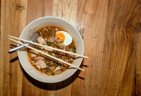 thai spicy noodle with pork and boild egg serve on wood tableの写真素材