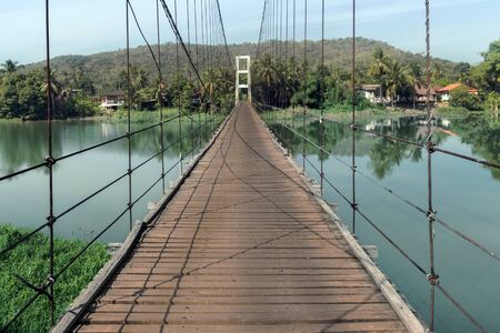wood hanking bridge cross the river to island at riverside of asian Thailandの写真素材