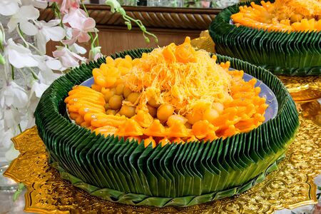mix thai yellow dessert with york egg serve on green banana leaf on wedding ceremonyの写真素材