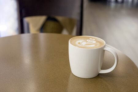a cup of late art coffee on cafe table in morning