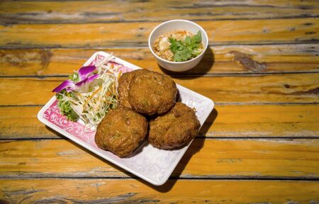fried spicy fish ball Thai food menu serve with vegetable and sweet sauce on old wood table that Thai treditional foodの写真素材