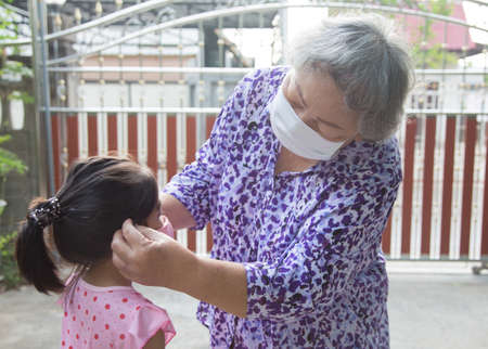 grand parent taking face mask to kids for protect corona virus pandemic before go outside homeのeditorial素材