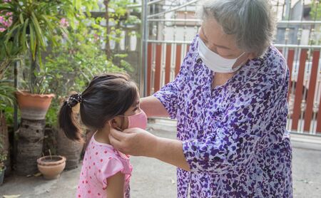 close up shot grand parent taking face mask to kids for protect corona virus pandemic before go outside homeの写真素材
