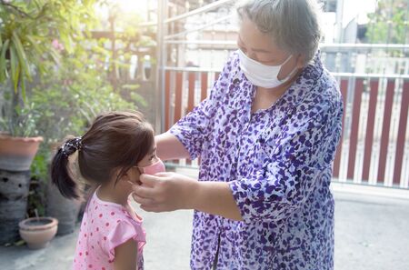 grand parent taking face mask to kids for protect corona virus pandemic before go outside homeの写真素材
