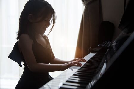 Asian girl kids practice playing pianoの写真素材