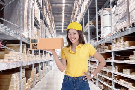 Asian woman show paper box inventory from warehouse with smile.の写真素材