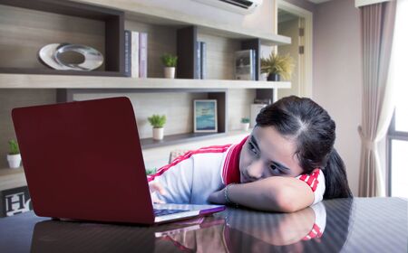 asian student learn form home with online network and device is not concentrait cause blue light on screen. closing school cause pandemic situation and social distance policy for asian countryの写真素材