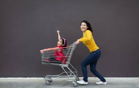 happy asian mother and daugther love shopping action with shopping cart on blank background.の写真素材
