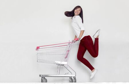 happy asian woman love shopping action with shopping cart on blank background.の写真素材