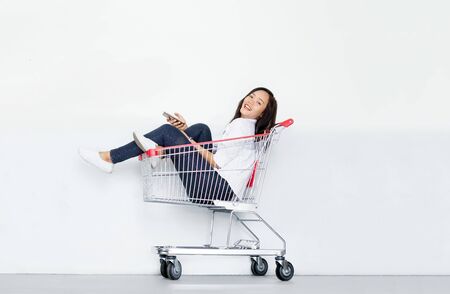 Asian girl use mobile phone in cart on whiteの写真素材
