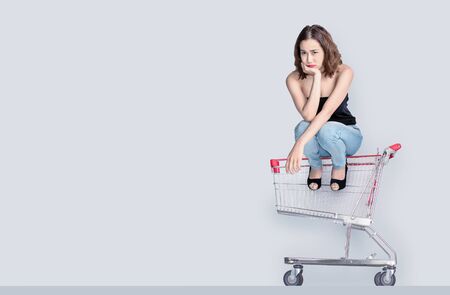 Worry face of asian woman waiting to shopping with sitting on empty shopping cartの写真素材