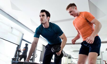 personal body building trainner at gym with dumbbell to making muscle and loss weight. Exercise need coach to support and teaching moving object and sport equipment on focus good shape.の写真素材