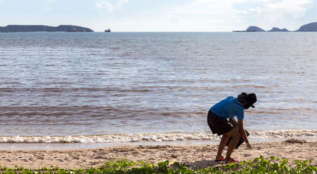 volunteer cleaning ocean beach after coronavirs pandemic with mask and gloveの写真素材