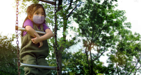 asian kid play stair at outdoor playpark garden with mask at coronavirus pandemicの写真素材