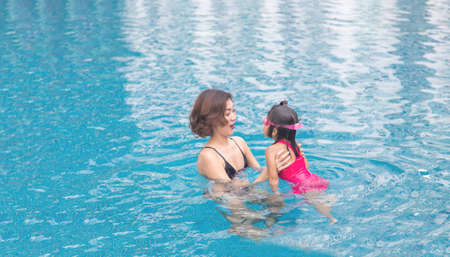 happy moment in summer with mother and kids in swimming poolの写真素材