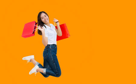 happy asian woman jumping with shopping paper bag on isolated background (include clipping part)