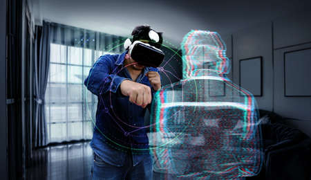 asian man wear vr glasses technology and exercise as boxing figthing sport with virtual enermy at home with graphic 3d illustrator.の写真素材