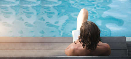 reading book near pool side and sunbathing for relax in summer vacation day with banner sizeの写真素材