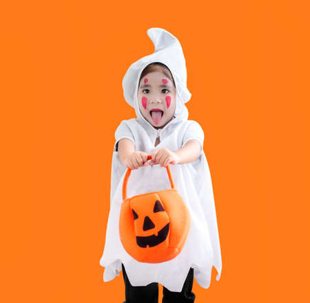 happy hallooween asian kid in ghost costum on orange isolated backgroundの写真素材