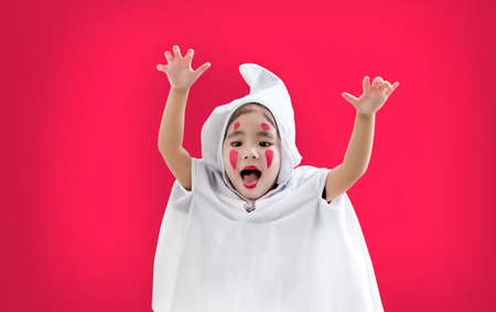 happy hallooween asian kid in ghost costum on red isolated background