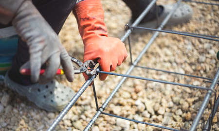 Close up shot on hands fixing steel reinforcement bars with officerの写真素材