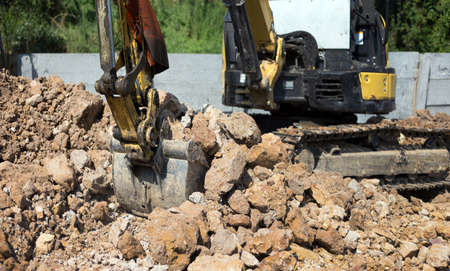 focus on scoop of excavator bulldozer in sandpit digging soil on construction siteの写真素材