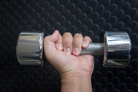Hand holding a dumbbell on rubber matの写真素材