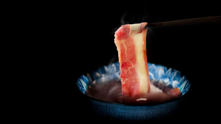 close up hot meat boild with chopstick on hot soup for asian food in dark backgroundの写真素材