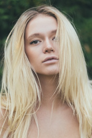 Attractive girl blonde with long hair, on green background.