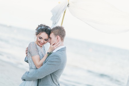 Delighted newly-weds cuddling at the seashore.の写真素材