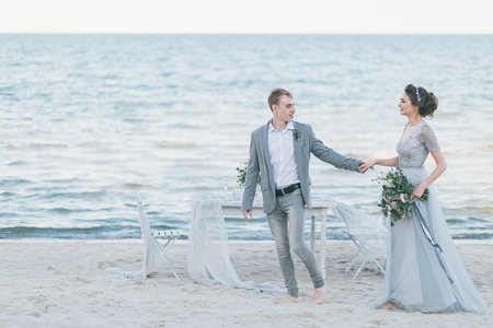 Delighted newly married couple holding hands by the sea.の写真素材