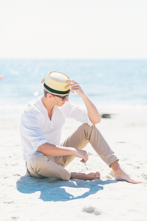 Good looking man in a hat sitting at the seashore.の写真素材