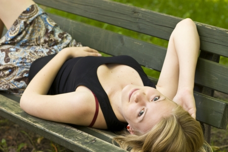 Woman lying on a park bench, portrait of a girlの写真素材
