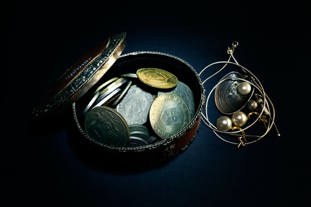 Various old coins from around the world in a brown box on a black backgroundの写真素材