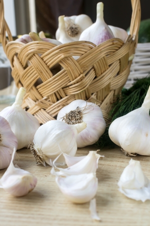 A basket of garlic, dill and garlic pieces on brown tableの写真素材
