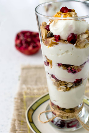 Dessert with yogurt, muesli and pomegranate seeds in a tall glassの写真素材