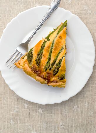 Sliced slice of tart with green asparagus and toasted cheese on the tableの写真素材