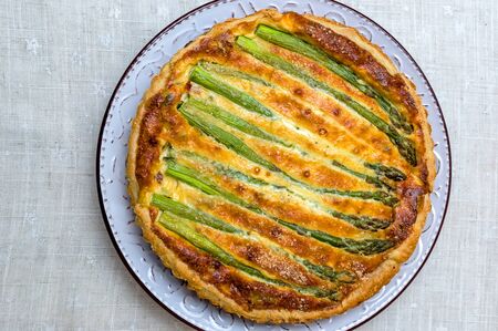Tart with green asparagus and toasted cheese on the table