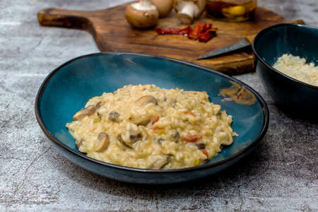 Risotto with mushrooms and sun-dried tomatoes in a blue bowlの写真素材