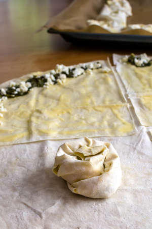 Sheets of dough for twisted patties with dock and white cheese on the table