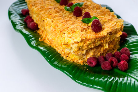 A piece of dessert Napolen garnished with raspberries for consumption on the tableの写真素材