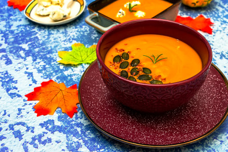 Diet pumpkin soup in a brown bowl on a blue backgroundの写真素材