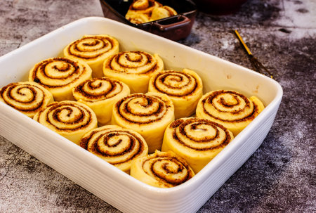 Ceramic plate with raw cinnamon rolls on a wooden tableの写真素材