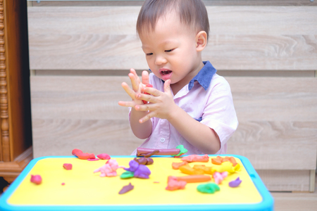 Cute little Asian 18 months / 1 years old toddler baby boy child having fun playing modeling clay / play dought at home, Improve & Increase Concentration In Kids, Creative play for toddlers conceptの写真素材