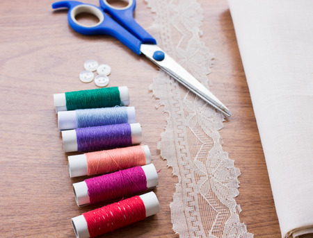 Sewing tools and sewing kit on wooden textured background