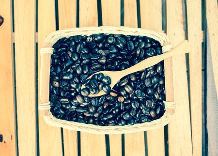 Coffee beans in basket on wooden tableの写真素材